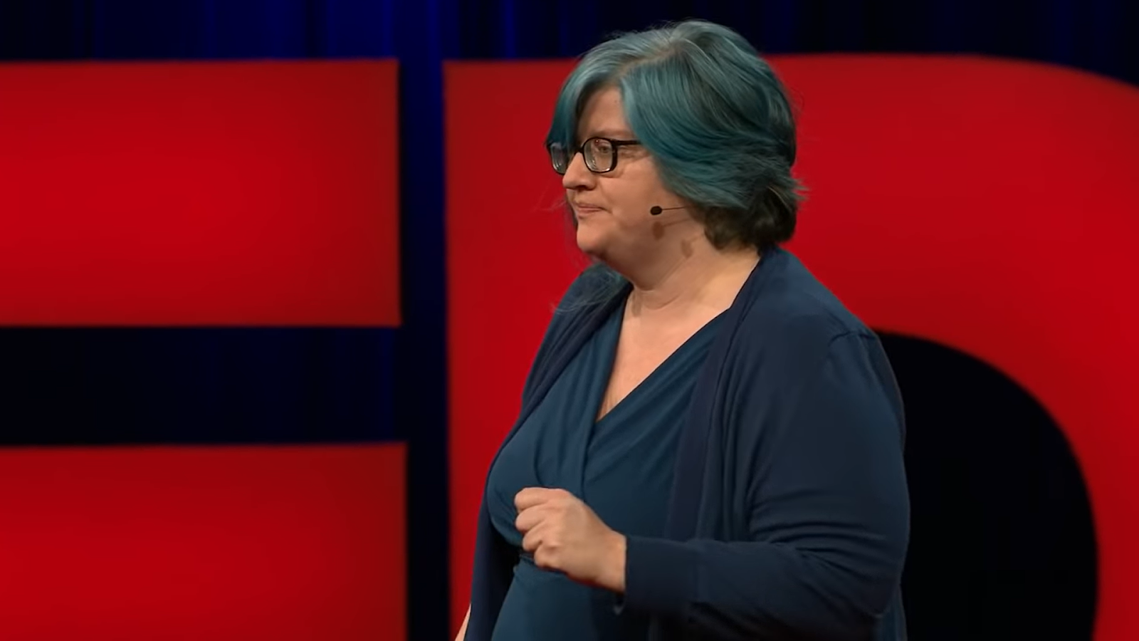 a side view of Cathy O'Neil on the stage, red words TED on the background