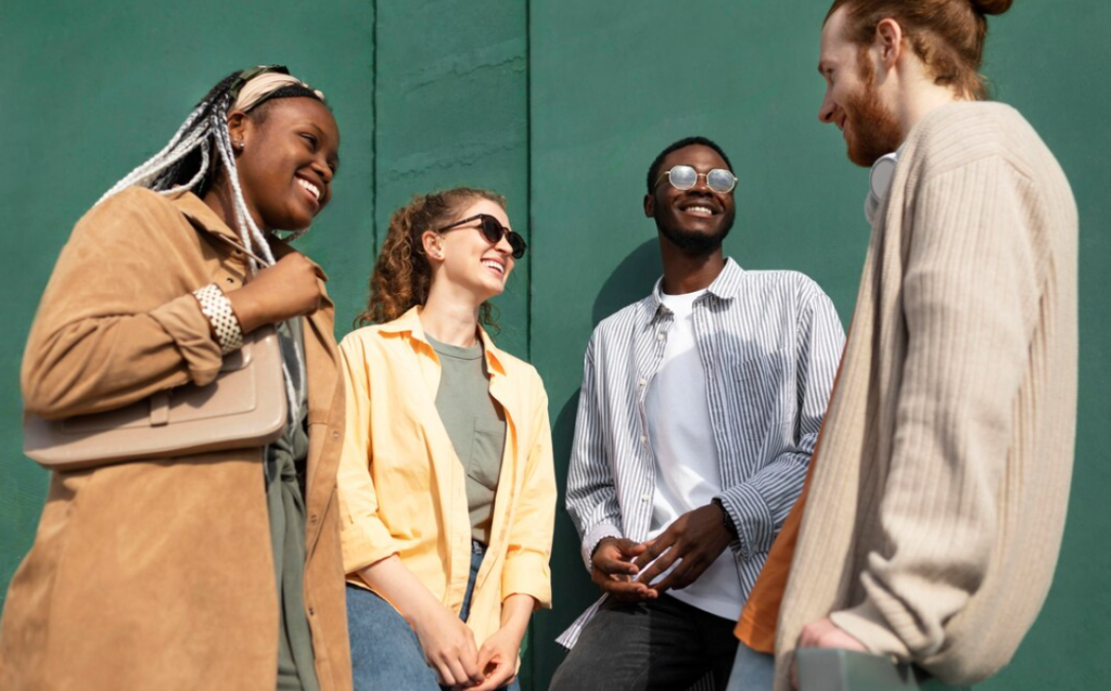 four diverse individuals laughing and engaging with each other against a green background